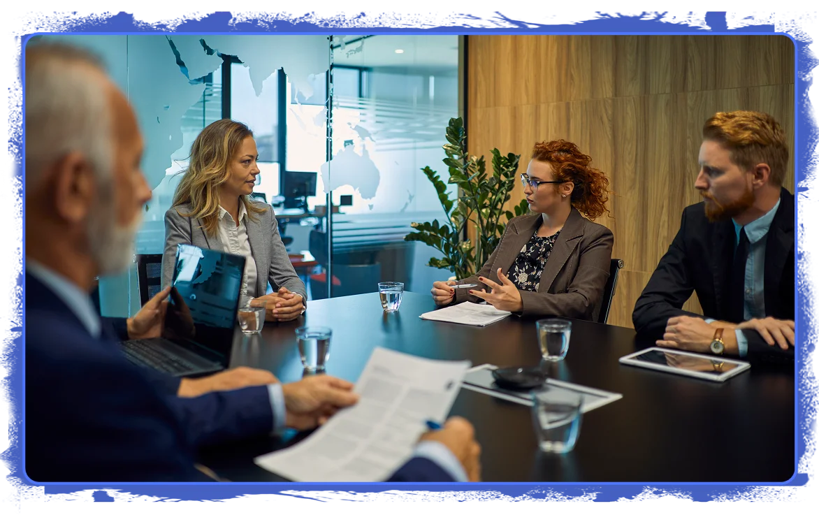 Business professionals in a meeting room discussing strategic pricing decisions, with documents, laptops, and tablets on the table, indicating a data-driven pricing conversation or negotiation.