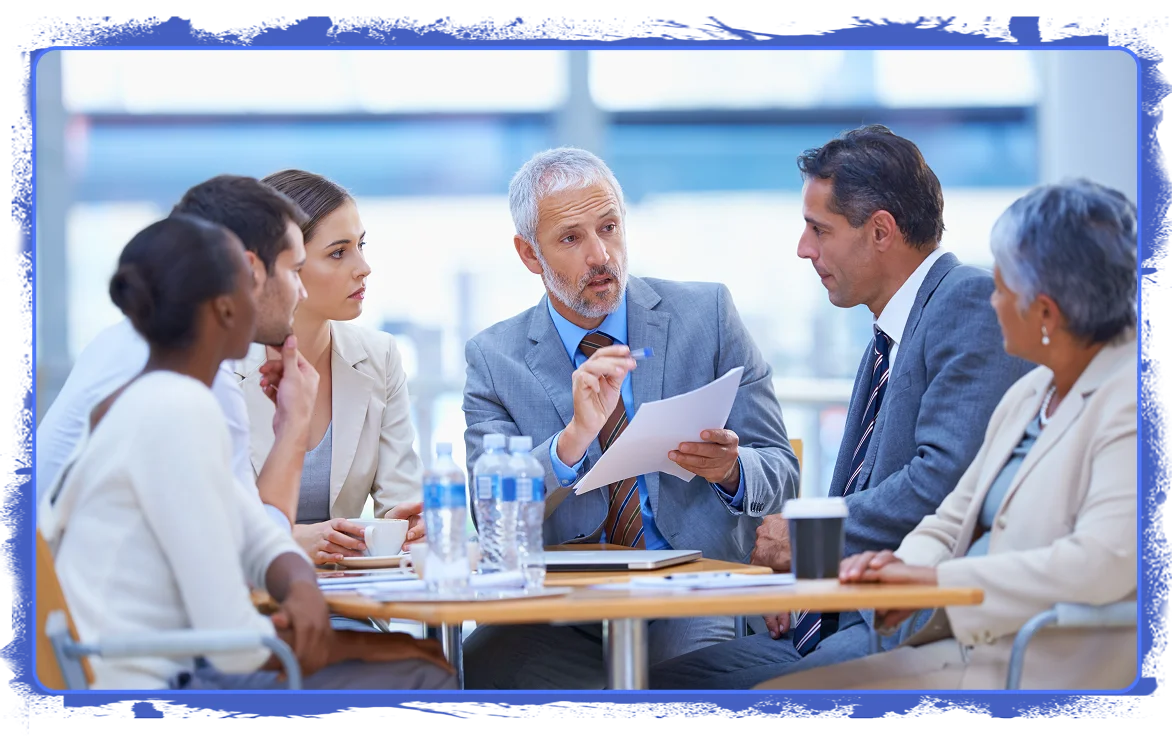 Business professionals engaged in a focused discussion around a pricing strategy, with the central figure explaining data or recommendations from a printed report while others attentively listen.